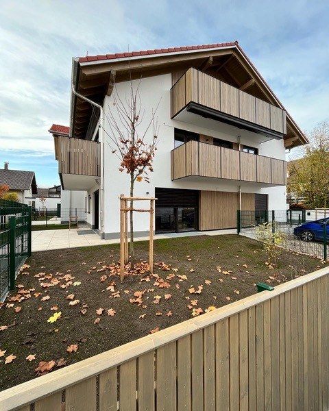 Mehrfamilienhaus in Oberhaching: Fassade mit Holzbalkonen und Garten