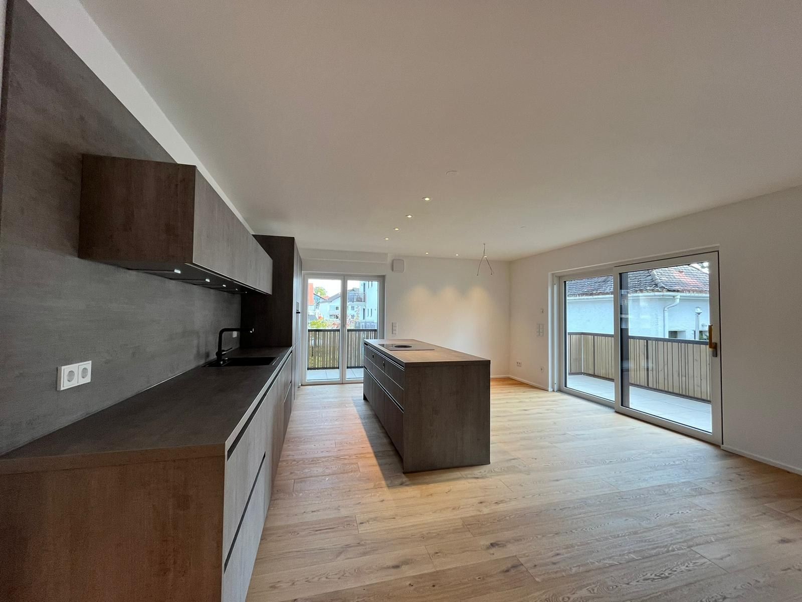 Mehrfamilienhaus in Oberhaching: Küche mit Kochinsel und Ausgang zur Terrasse